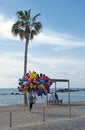 a balloon seller walks past two tourists sat on the beach in Paphos cyprus