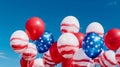 Balloons in the colors of the United States of America flag float against the blue sky.