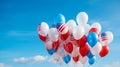 Balloons in the colors of the United States of America flag float against the blue sky.