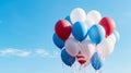 Balloons in the colors of the United States of America flag float against the blue sky.