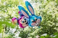 Balloons filled with helium in form of rabbit and mouse in children\'s park against the backdrop of green trees