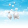 Balloons floating in blue sky with fluffy white clouds