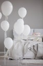 Balloons in front of bed with blanket and pillows