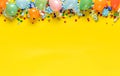 Balloons and various party decorations on yellow background with copy space. Birthday background top view