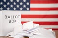 Ballot Box with votes on table before counting with US flag as background concept of Ballot or vote Counting after US election Royalty Free Stock Photo
