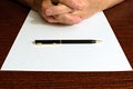 Ballpoint pen on a blank white sheet of paper. folded fingers Royalty Free Stock Photo