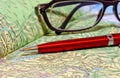 Ballpoint pen and glasses lie on geographical atlas