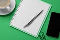 Ballpoint pen, notebook and smartphone on green background, flat lay Royalty Free Stock Photo