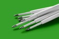 Ballpoint pen refills. Plastic refills for ballpoint pens. Pile of white ink refills on a green