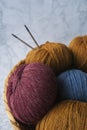 Balls of colorful knitting yarns lie in a wicker basket on a marble background. There are two knitting needles in the yarn Royalty Free Stock Photo