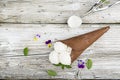 Balls of creamy vanilla ice cream in a crispy chocolate mug with edible viola flowers and mint leaves on a dark Royalty Free Stock Photo