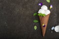 Balls of creamy vanilla ice cream in a crispy chocolate mug with edible viola flowers and mint leaves on a dark Royalty Free Stock Photo