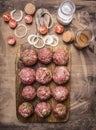 Balls of minced meat on a cutting board with cherry tomatoes and seasonings wooden rustic background top view close up