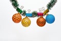 Balls with ornaments hang on shimmering green tinsel. Tinsel with pinned christmas ornaments, white background, copy