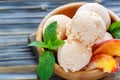 Balls peach ice cream in a wooden bowl closeup.