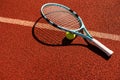 Balls and racket are lying on clay brown professional tennis court Close up of tennis balls and racket on dross at Royalty Free Stock Photo