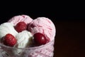 Balls of strawberry, cherry and vanilla ice cream in a glass vase, with fresh berries on a dark background