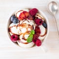 Balls of vanilla ice cream in mug with raspberry and blueberries, chocolate syrup topping. Top view summer dessert, white, bright