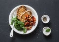 Balsamic marinated cherry tomato salad with pine nuts, spinach and grilled bread on dark background, top view