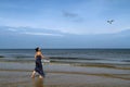 Baltic sea, woman walking along the beach and feeding white gu Royalty Free Stock Photo