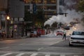 Baltimore Downtown with Traffic in Background. People Crossing Street. Pipe Vapour Steam in Background