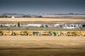 Heavy equipment parked in single file at a commercial development site next to QE2 Highway near Cross Iron Mills Shopping Center.