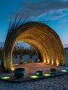 Bamboo amphitheater in a cyclone-prone desert, bioluminescent lights illuminating ancient ceramics and multiverse artifacts
