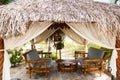 Bamboo benches with cushions, low round table are in an open thatched pavilion Royalty Free Stock Photo