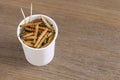 Bamboo Caterpillar insects for eating as food. Worm deep-fried crispy snack in disposable cup for take-away home on wood table
