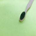 Charcoal infused bamboo toothbrush on green background. cool tone.