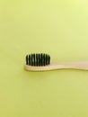 Charcoal infused bamboo toothbrush on yellowish green background. Vertical.