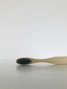 Charcoal infused bamboo toothbrush on marble white background. Vertical.