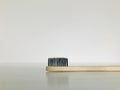 Charcoal infused bamboo toothbrush on marble white background. Details.