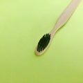 Charcoal infused bamboo toothbrush on green background. warm tone.