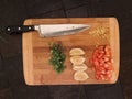 Bamboo cutting board with chef knife and prepared chives lemon zest and tomatoes