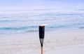 Bamboo fire torch on sunset tropical beach - Evening summer beach background Royalty Free Stock Photo