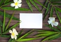 Bamboo leaf frame on rustic wooden background. Blank paper in bamboo leaf and frangipani flower. Royalty Free Stock Photo