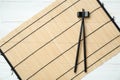 Bamboo mat with pair of black chopsticks and rest on white wooden table, top view Royalty Free Stock Photo