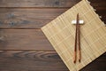 Bamboo mat with pair of chopsticks and rest on wooden table, top view. Space for text Royalty Free Stock Photo