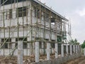 Bamboo scaffolds are installed around the constructing house for cement plastering work on the high outer wall of the house