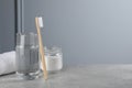 Bamboo toothbrush, glass of water and jar of baking soda on light grey table, space for text Royalty Free Stock Photo