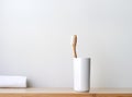 Bamboo toothbrush, glass of water, white a cotton towel and powder for brushing your teeth in jar. light gray concrete