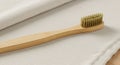 Bamboo toothbrush with light bristles placed on a beige textile surface. The handle Royalty Free Stock Photo