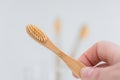 bamboo toothbrush.Teeth cleaning.Toothbrush with toothpaste in hand under tap water in bathroom. Hand takes a toothbrush