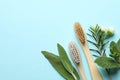 Bamboo toothbrushes, beautiful flowers and herbs on turquoise background, flat lay. Space for text