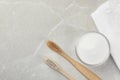 Bamboo toothbrushes, glass bowl of baking soda and towel on light grey marble table, flat lay. Space for text