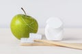 Bamboo toothbrushes, green apple and dental floss on white background