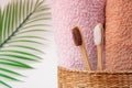 Bamboo toothbrushes with towels in a wicker wooden basket and palm leaves with copy space on white background. Spa, healthy lifest Royalty Free Stock Photo