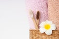 Bamboo toothbrushes with towels in a wicker wooden basket and  plumeria flower with copy space on white background. Spa, healthy l Royalty Free Stock Photo