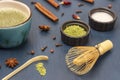 Bamboo whisk and measuring spoon on table. Green matcha powder and milk in bowls